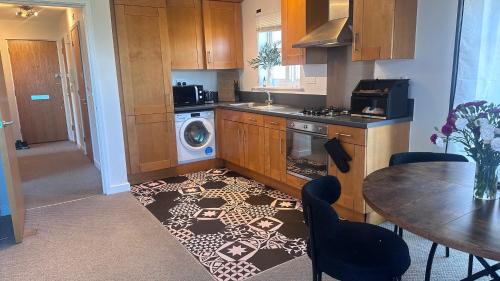 a kitchen with a table and a kitchen rug at Modern 2 bed flat with parking by Bluewater shopping mall in Greenhithe