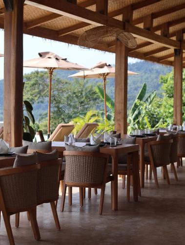 a dining room with tables and chairs and umbrellas at Atalaya Resort El Nido in El Nido