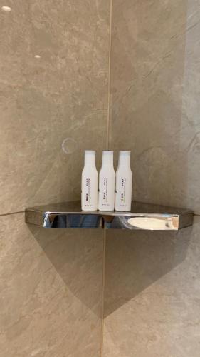 three white bottles sitting on a shelf in a shower at SENNA SUNSHINE INTERNATIONAL HOTEL in Sihanoukville