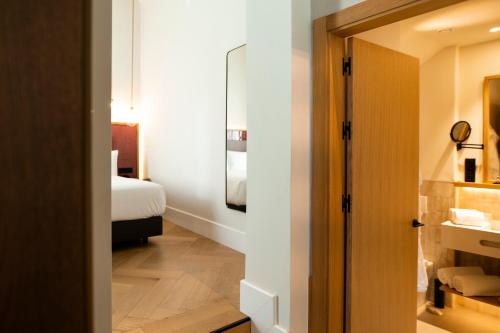 a room with a bedroom with a bed and a bathroom at Legado Magdalena Hotel in Seville