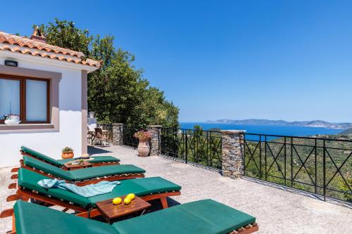 a patio with green chairs and a view of the ocean at Kastanies Ananias Skopelos in Skopelos Town