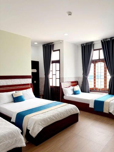 a bedroom with two beds and two windows at Yen Phu Hotel Tuy Hòa in Tuy Hoa