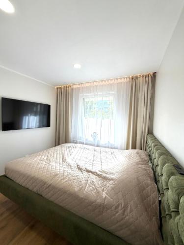 a bedroom with a bed with a couch and a television at DEUX rooms in Liepāja