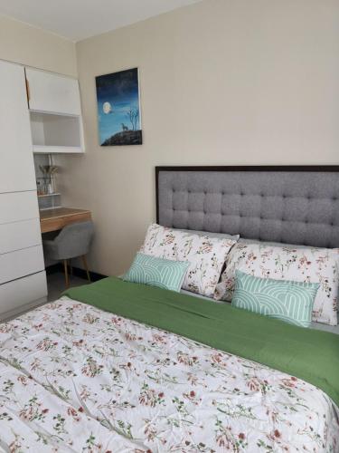 a bedroom with a large bed with a green comforter at Villa Bosque - Forest Residences in Antipolo
