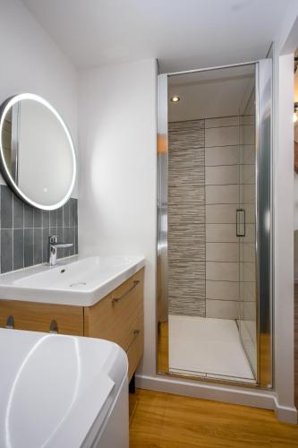 a bathroom with a shower with a sink and a mirror at Le 38-Appart'Hôtel-GregIMMO in Montbéliard
