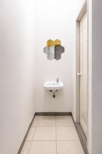 a white bathroom with a sink and a mirror at Rays Residence in Jakarta