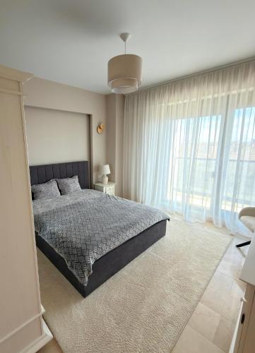 a bedroom with a bed and a large window at Sophia Luxury Residence in Mamaia