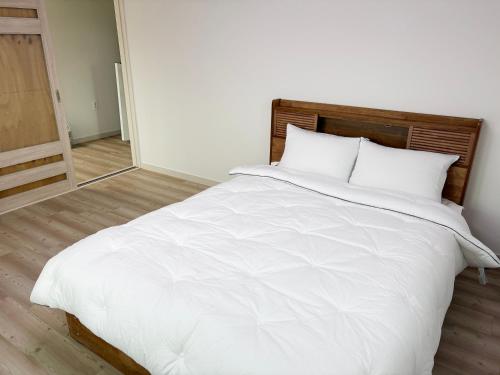 a bed with white sheets and pillows in a room at 깨비하우스202 in Wŏlsan