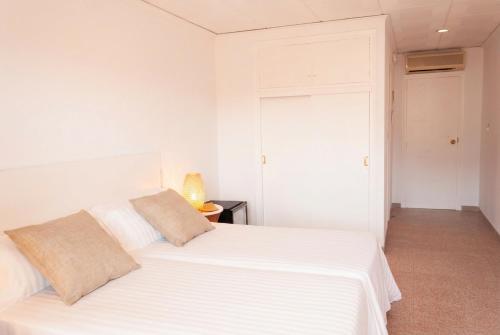 a white bedroom with a white bed with two pillows at Hostal Comercio in Denia