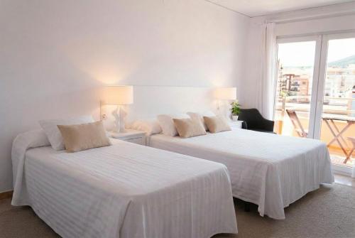 two beds in a white room with a window at Hostal Comercio in Denia