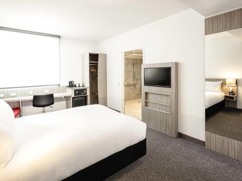 a hotel room with a bed and a flat screen tv at Ibis Mackay in Mackay