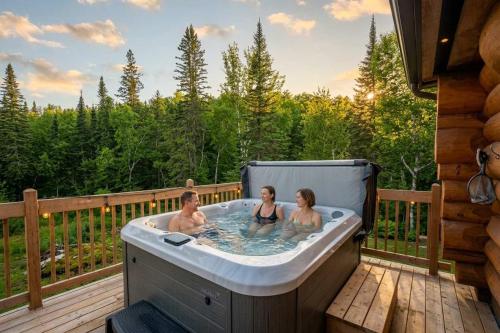 a group of three people in a hot tub on a deck at Spa & Pool table - Le Massif in Saint Adolphe D'Howard