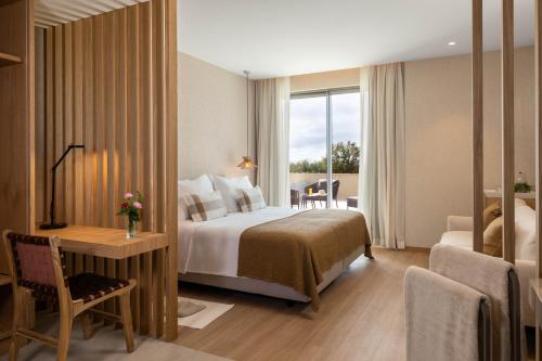 a hotel room with a bed and a desk and a window at Legacy Ithos Boutique Hotel in Porto Santo