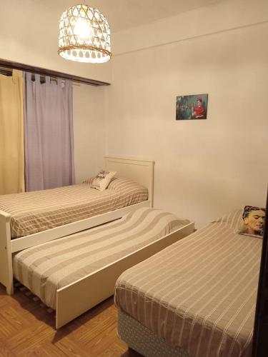 a bedroom with two beds and a chandelier at FRIDA APARTMENT remis gratis a Ezeiza in Ezeiza