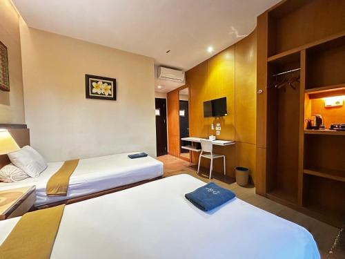 a hotel room with two beds and a desk at Hotel De Green Lampung in Lampung