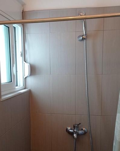 a shower with a hose in a bathroom at Sofia Comfort Apartment in Nivicë