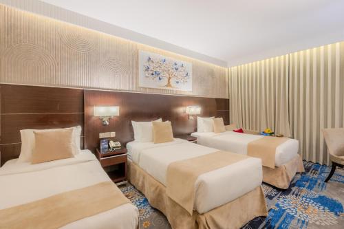 a hotel room with two beds and a desk at The Venue Al Harithia Hotel in Medina