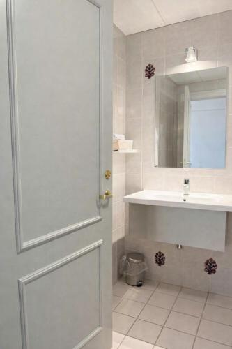 a bathroom with a door and a sink and a mirror at Hotel Schaumburg in Holstebro