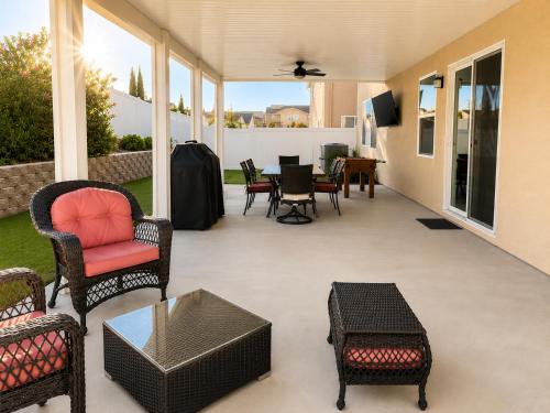 a screened porch with chairs and a table and a television at Windridge Manor - Wine Country Retreat with 6 Beds, Garden, Pool, Games & BBQ in Winchester