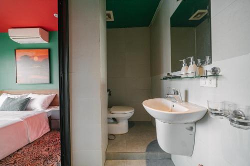 a bathroom with a sink and a toilet and a bed at Modapick Bạch Đằng - Living in the nature garden with full river view in Hanoi