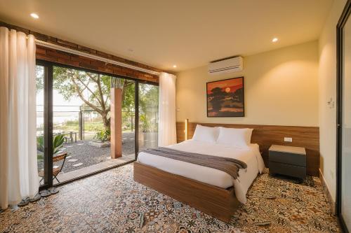 a bedroom with a bed and a sliding glass door at Modapick Bạch Đằng - Living in the nature garden with full river view in Hanoi