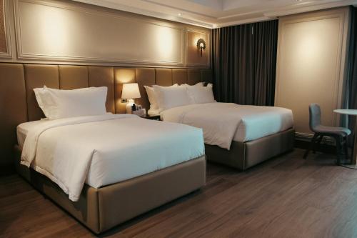 a hotel room with two beds and a chair at Radiant Hotel and Events in San Fernando