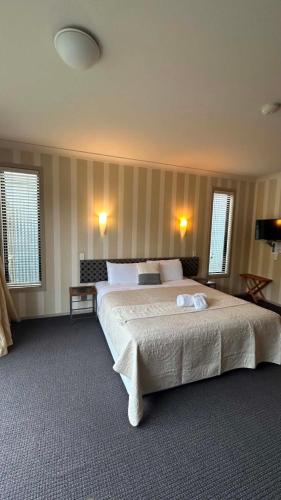 a bedroom with a large bed and two windows at Hawkdun Lodge Motel in Ranfurly