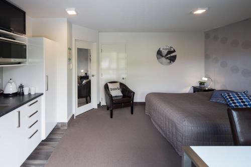 a hotel room with a bed and a chair at Commodore Motel in Dunedin