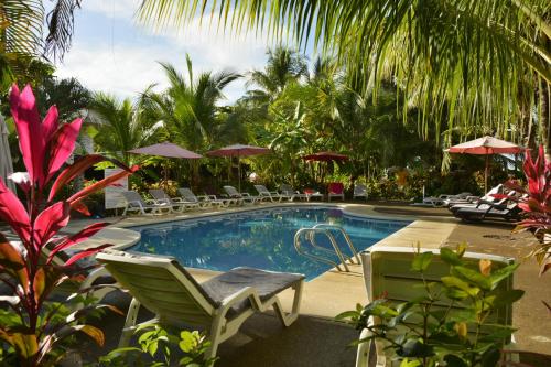 a pool with chairs and umbrellas in a resort at Hotel Pochote Grande in Jacó