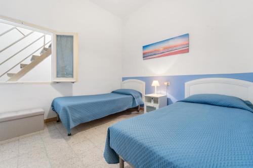 a bedroom with two beds and a window at Al centro del Borgo in Calasetta