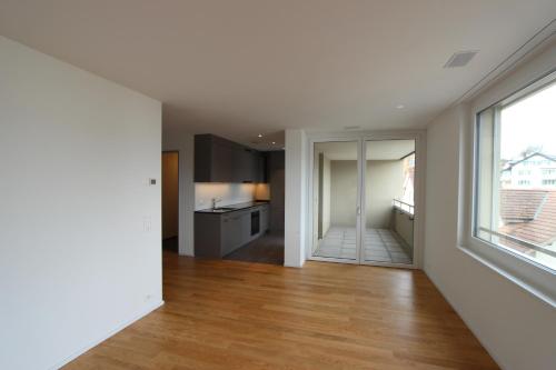 eine leere Küche und ein Wohnzimmer mit einem großen Fenster in der Unterkunft Valo Central - Wohnung mit Arbeitsplatz am Zürichsee in Pfäffikon