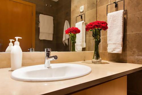 a bathroom sink with red flowers in a vase at Finest Rentals - Expo Riverside in Lisbon