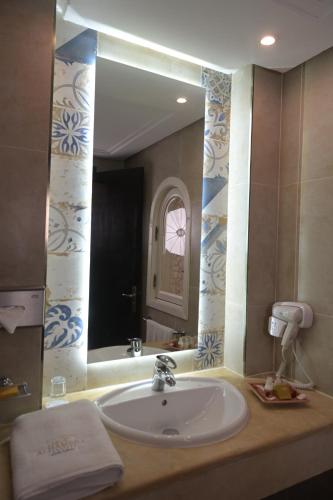 a bathroom with a sink and a large mirror at Alhambra Thalasso in Hammamet