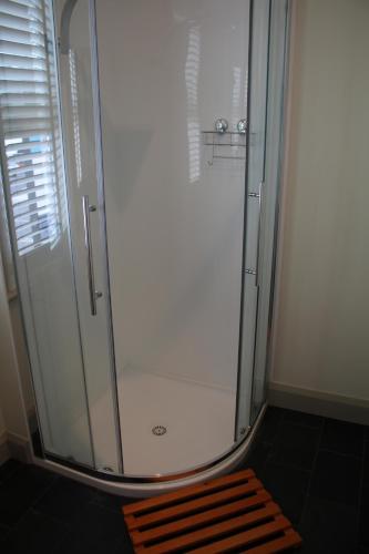 una ducha con puerta de cristal en un baño en The Tasmanian Inn, en Hobart