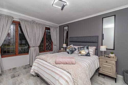 a bedroom with a large bed and windows at Ruby on Hamilton in Windsor Park