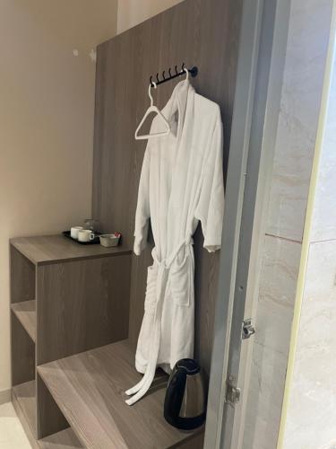 a white robe hanging on a hanger in a bathroom at Raghav Residency in Vellore