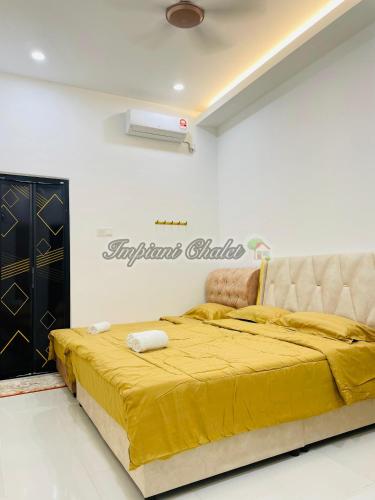a bedroom with a large bed with a yellow blanket at Impiani Chalet with Private Pool in Kuala Terengganu