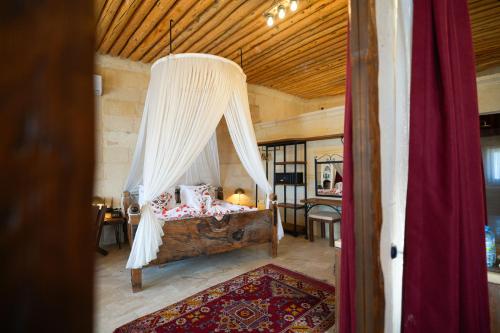 a bedroom with a bed with a canopy at Helike Cave Suites in Uçhisar
