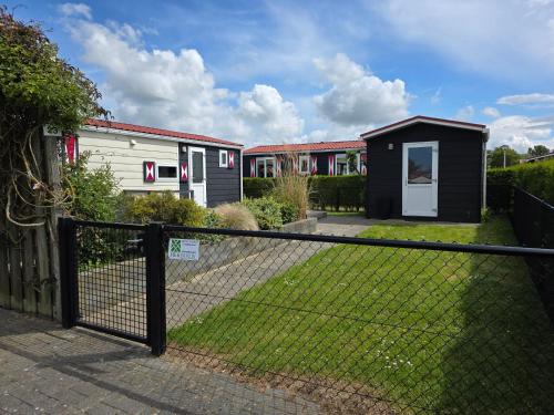 a fence in front of a house at Chalet Olm Ferienpark Olmenduin Zeeland 4 Pers familienfreundlich Hunde willkommen in Serooskerke