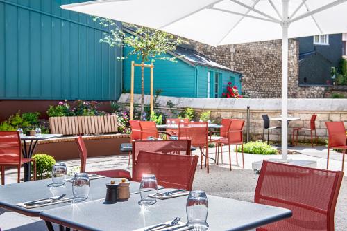 a restaurant with tables and chairs and an umbrella at Radisson Blu Hotel, Rouen Centre in Rouen