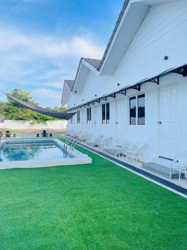 an exterior view of a white building with a pool and green grass at Impiani Chalet with Private Pool in Kuala Terengganu