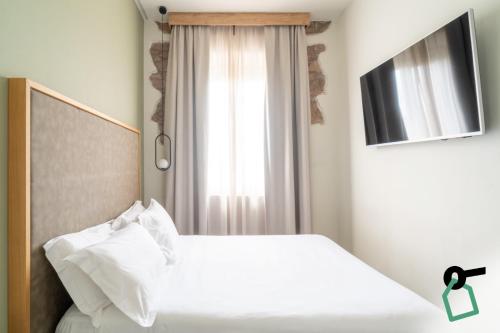 a bedroom with a white bed and a window at Hotiday Relais Costa degli Etruschi in Vada
