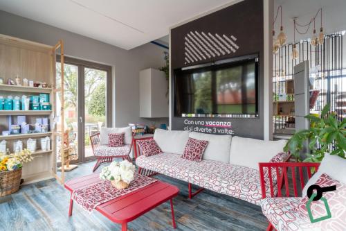 a living room with red and white chairs and a couch at Hotiday Relais Costa degli Etruschi in Vada