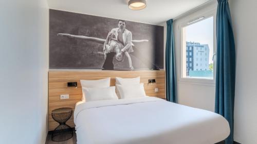 a bedroom with a bed and a painting on the wall at Campanile PRIME - Lyon Meyzieu Eurexpo Arena Stadium in Meyzieu