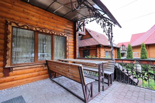 a wooden cabin with a bench and a table on a balcony at Садиба "Едем" in Mykulychyn