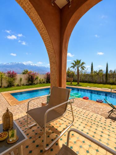a patio with a chair and a swimming pool at VILLA Les 3 Palmiers in Amezrou