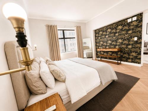 a white bedroom with a bed and a lamp at Cape Town Panorama Luxe Suite in Cape Town