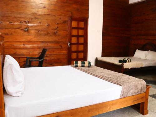 two beds in a room with wooden walls at RT Point Gombamiya Hotel Kandy in Huluganga