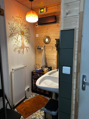 a bathroom with a sink and a tree mural on the wall at l'Orée des Moraines in Monnet-la-Ville