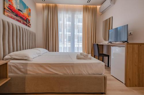 a bedroom with a bed with a television and a desk at Queen Residence & Hotel in Shëngjin